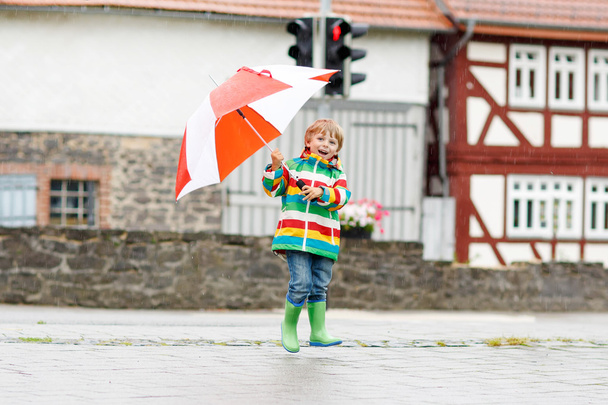 kleiner blonder Junge geht mit großem Regenschirm im Freien - Foto, Bild