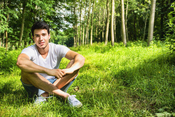 Fit handsome young man relaxing lying on lawn grass - Fotó, kép