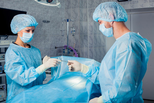 Chirurgen-Team arbeitet mit Überwachung der Patientin im Operationssaal. Brustvergrößerung. - Foto, Bild