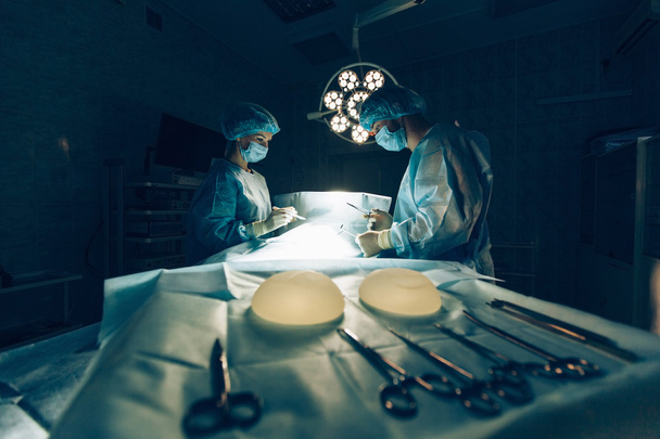 Surgeons team working with Monitoring of patient in surgical operating room.breast augmentation. - Fotografie, Obrázek