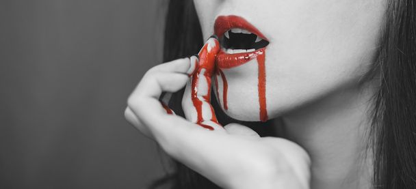Vampire woman wipes blood from lips - Foto, Imagen