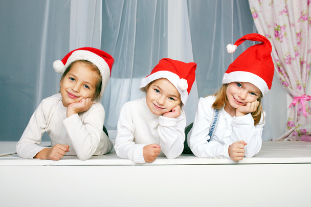 Três crianças em chapéus de Natal
 - Foto, Imagem