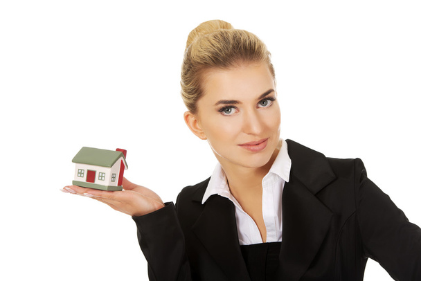 Happy businesswoman holding a house model - Zdjęcie, obraz