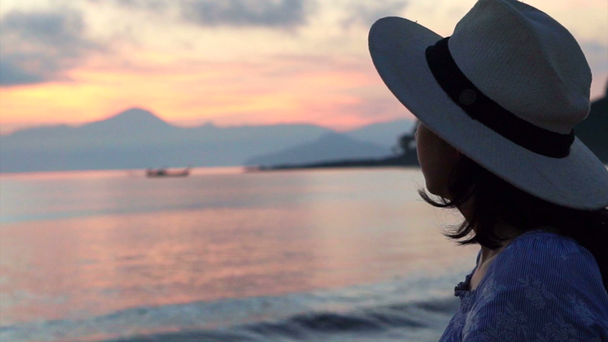 Videó az ázsiai nő sziluett, élvezi Seascape kalap alatt napkelte. gyönyörű trópusi strandok és a táj - Felvétel, videó