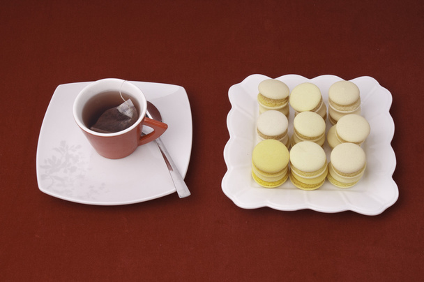 φλιτζάνι τσάι και macaroons στοιβάζονται και να ευθυγραμμιστούν για μια tablecl βελούδο - Φωτογραφία, εικόνα