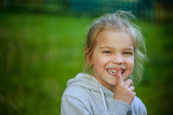 Χαμογελαστά κοριτσάκι σε βάζει το δείκτη στα χείλη - Φωτογραφία, εικόνα
