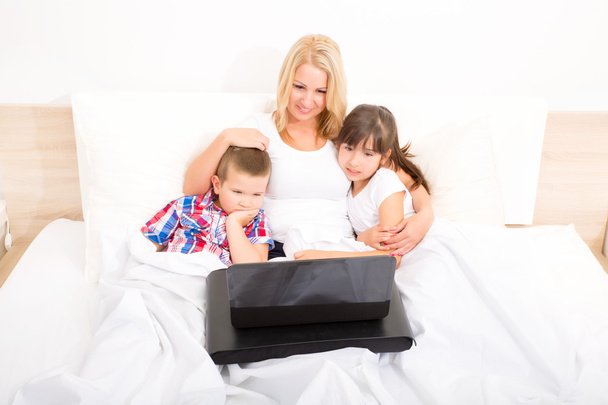 Mother with her kids using a laptop in bed - Foto, Imagem