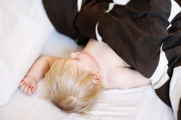 Toddler sleeping in a bed - Foto, afbeelding