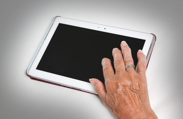 Hand der Seniorin entspannt sich und liest den Bildschirm ihres Tisches - Foto, Bild
