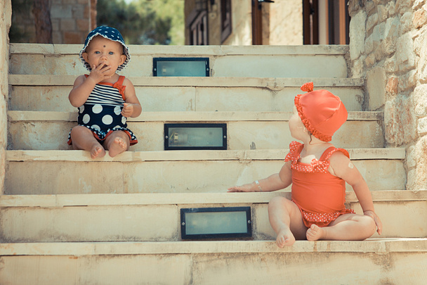 zwei süße kleine Mädchen sitzen auf der Treppe in der Straße - Foto, Bild