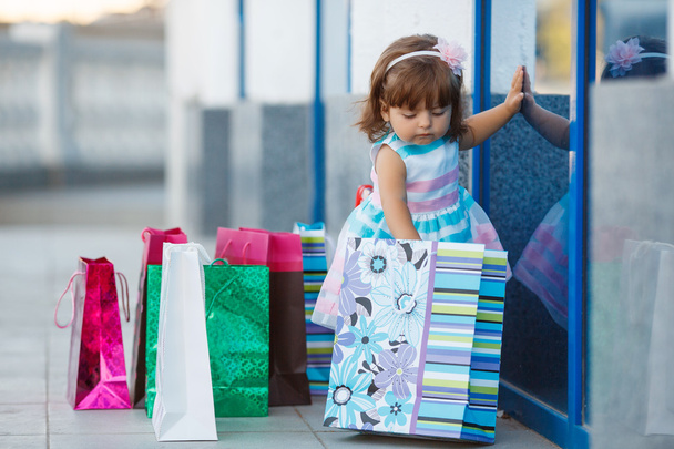 little girl and lots of colorful bags - Foto, Imagem