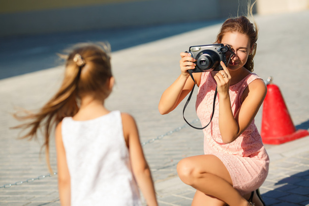 Mom photographs her daughter on the street in the city in the summer - Foto, afbeelding