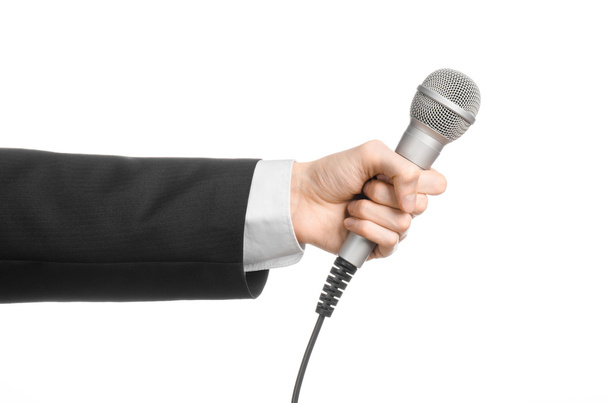 Business and speech topic: Man in black suit holding a gray microphone on an isolated white background in studio - Photo, Image