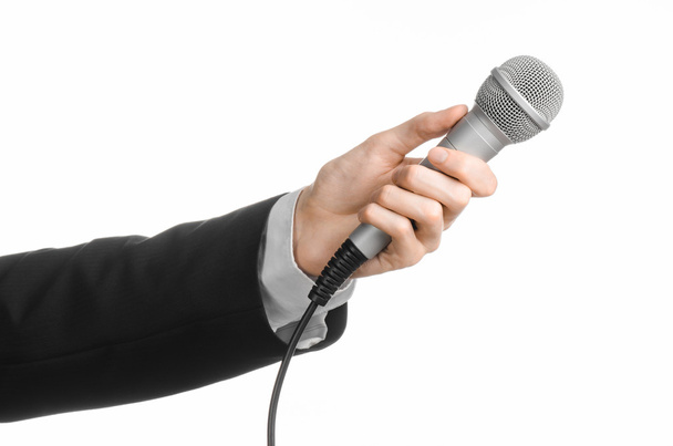 Business and speech topic: Man in black suit holding a gray microphone on an isolated white background in studio - Fotografie, Obrázek