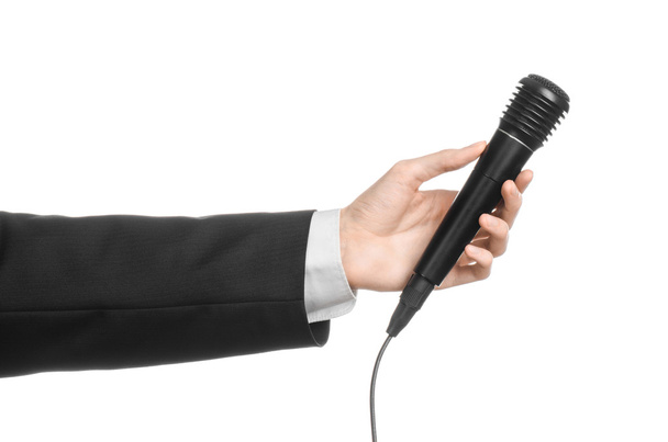 Business and speech topic: Man in black suit holding a black microphone isolated on white background in studio - Photo, Image