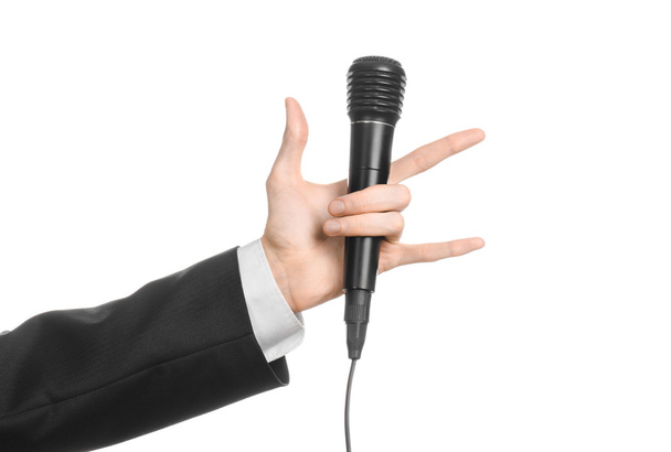 Business and speech topic: Man in black suit holding a black microphone isolated on white background in studio - Fotografie, Obrázek