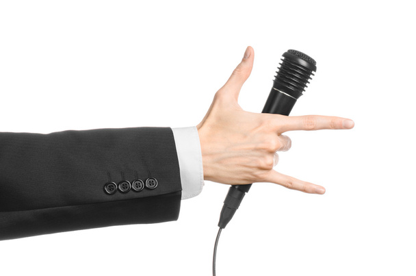 Business en spraak onderwerp: Man in zwart pak houden een zwarte microfoon geïsoleerd op een witte achtergrond in studio - Foto, afbeelding
