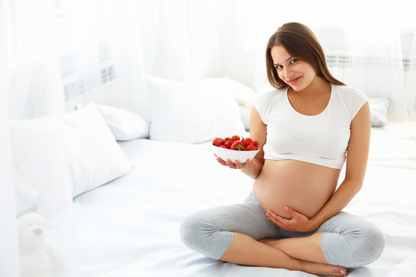 Pregnant Woman Eating Strawberry at home. Healthy Food Concept. - Foto, imagen