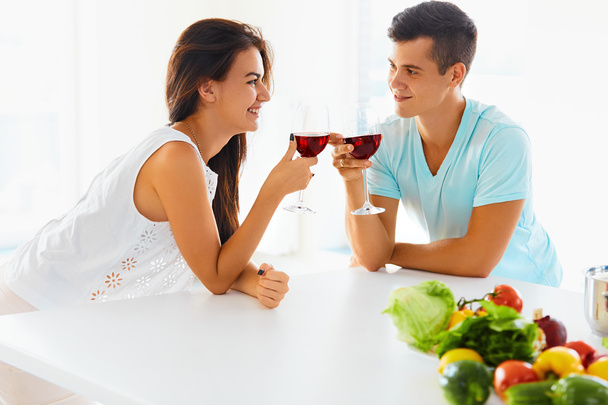 Wife and husband with wine and vegetables in kitchen - Foto, Imagen