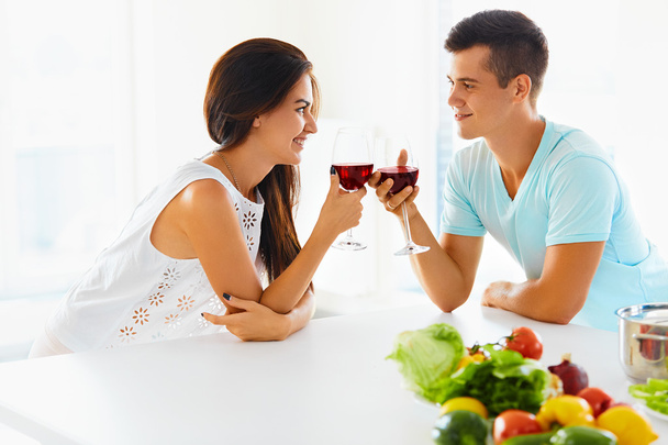 Smiling couple with wine and vegetables in kitchen - Zdjęcie, obraz