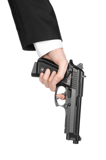 Firearms and security topic: a man in a black suit holding a gun on an isolated white background in studio - Φωτογραφία, εικόνα