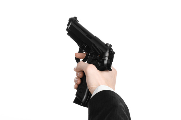 Firearms and security topic: a man in a black suit holding a gun on an isolated white background in studio - Foto, immagini