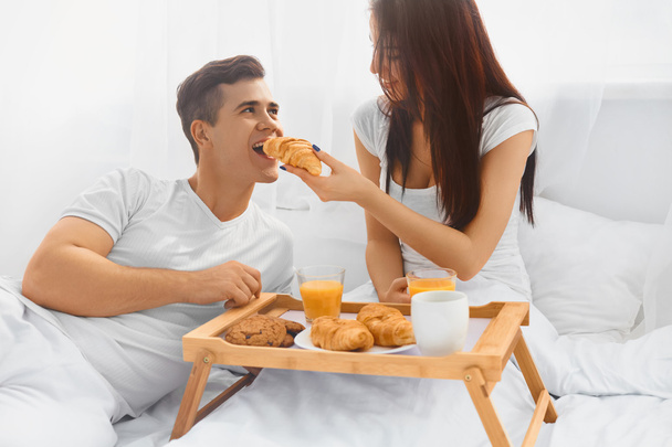 Young woman feeding man in bed - Фото, зображення