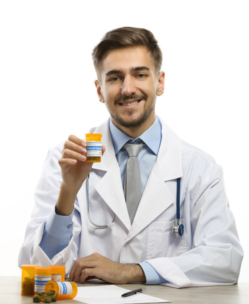 Доктор тримає пляшку з медичним канабісом ізольовано на білому
 - Фото, зображення