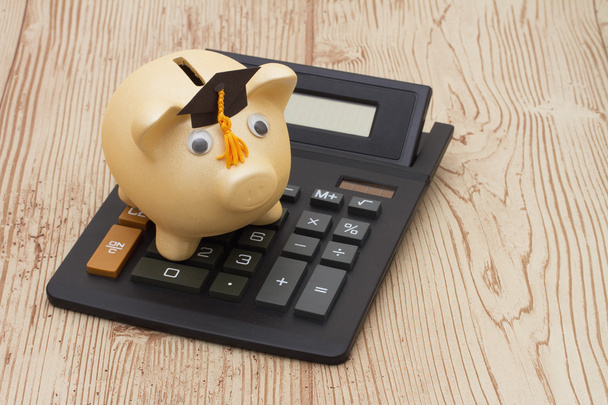 A golden piggy bank with grad cap and calculator on wood backgro - Photo, Image