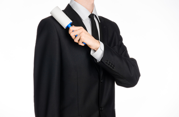 Kuivapesu ja liiketoiminnan teema: mies mustassa puvussa tilalla sininen tahmea harja vaatteiden ja huonekalujen puhdistamiseen pölystä eristetty valkoisella taustalla studiossa
. - Valokuva, kuva