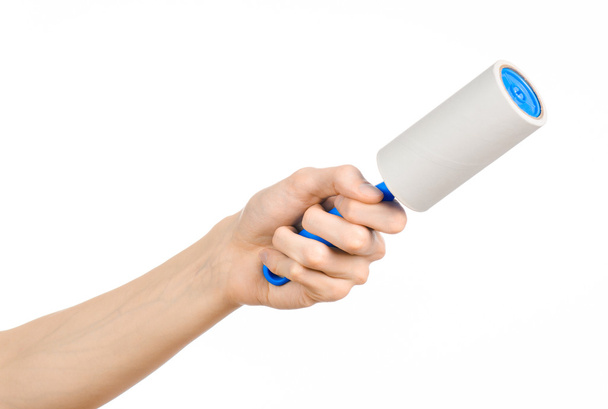Clean clothes and cleaning the house topic: human hand holding a blue sticky brush for cleaning clothes and furniture from dust isolated on white background in studio. - Photo, Image