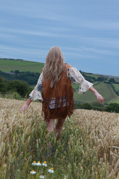 Indietro di una ragazza adolescente che cammina in un campo di grano
 - Foto, immagini
