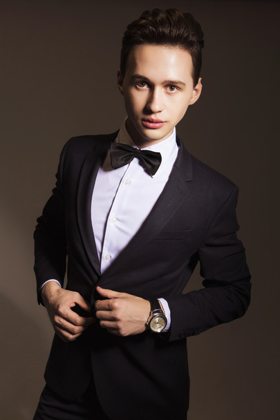 Young handsome brunette macho businessman in black suit and bow - Fotó, kép