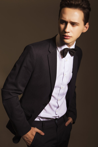 Young handsome brunette macho businessman in black suit and bow - Fotó, kép