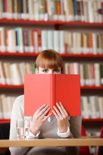 Girl hiding behind the book on library - Fotó, kép