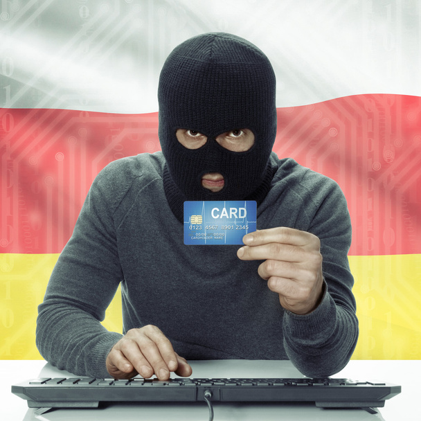 Dark-skinned hacker with flag on background holding credit card in hand - South Ossetia - Foto, imagen