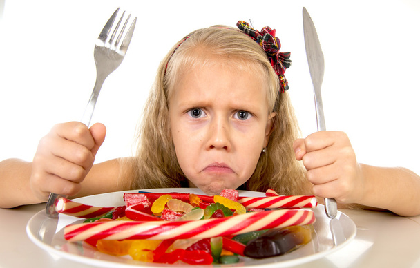 pretty Caucasian female child eating dish full of candy in sweet sugar abuse dangerous diet - Fotó, kép