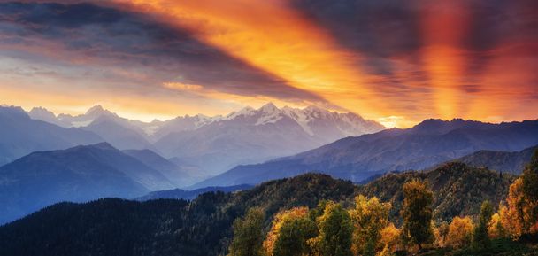 Sunset over snow-capped mountain peaks. The view from the mounta - Photo, Image