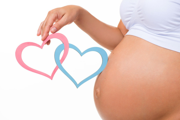 Pregnant belly with blue and pink heart. Horizontal closeup. Determine the sex of the child: twins, girl or boy. - Fotografie, Obrázek