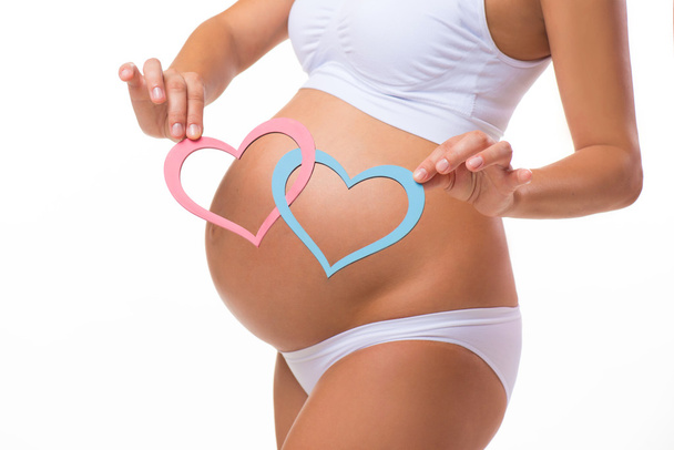 Pregnant belly with blue and pink heart. Horizontal closeup. Determine the sex of the child: twins, girl or boy. - Foto, Imagen