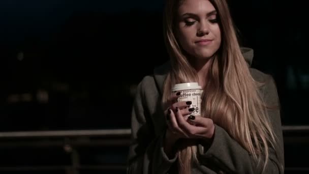 Meisje tiener in de straat bij nacht drinken van koffie en wachten - Video