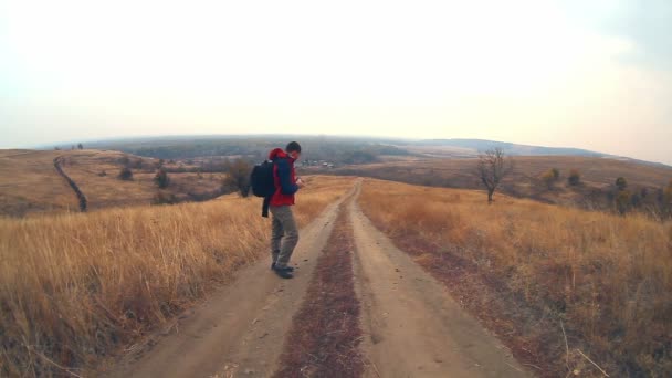 escursionista viaggiatore uomo con lo zaino in autunno è sulla strada per la natura è solitario albero viaggi
 - Filmati, video