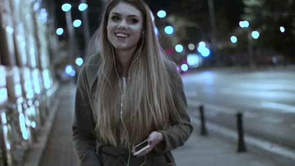 Woman listening music on cellphone walking evening time - Footage, Video