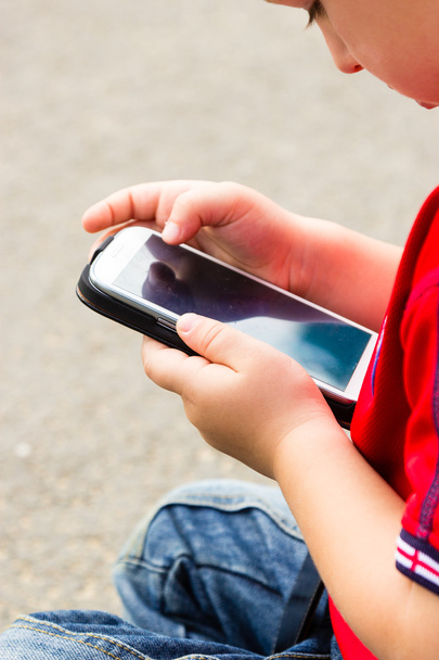 Little boy child playing games on mobile phone outdoor - Φωτογραφία, εικόνα