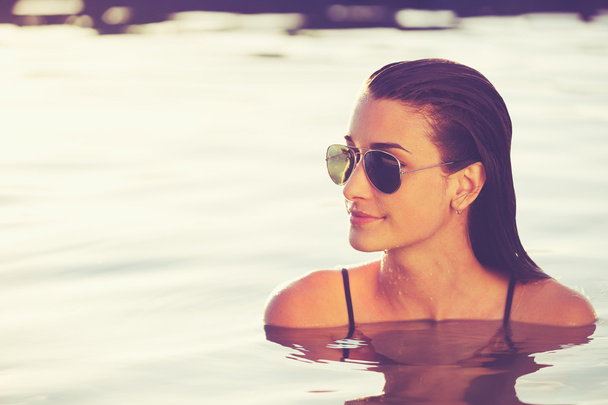 Beautiful Woman Relaxing in Pool at Sunset - Photo, image
