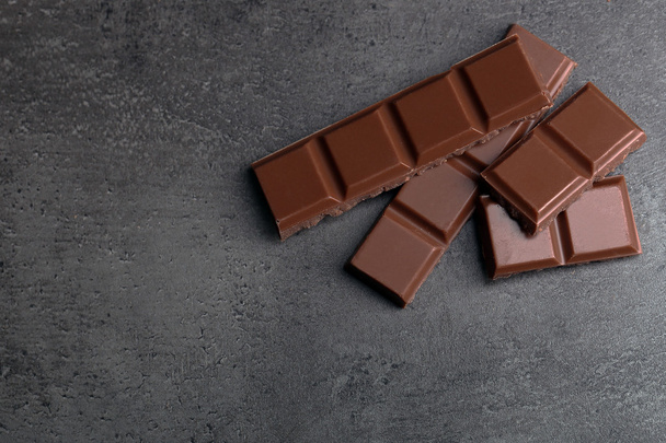Milk chocolate pieces on gray background - Φωτογραφία, εικόνα