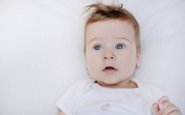 portrait of cute little baby boy lying on soft white pillow - Photo, Image