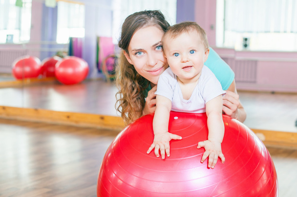 Mother with happy baby doing exercises with gymnastic ball - Φωτογραφία, εικόνα