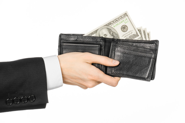 Money and business topic: hand in a black suit holding a wallet with dollar banknotes isolated on white background in studioMoney and business topic: hand in a black suit holding a wallet with dollar - Foto, immagini
