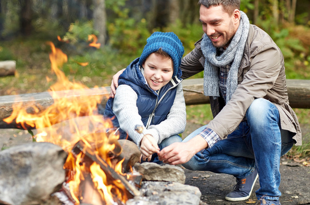 father and son roasting marshmallow over campfire - 写真・画像